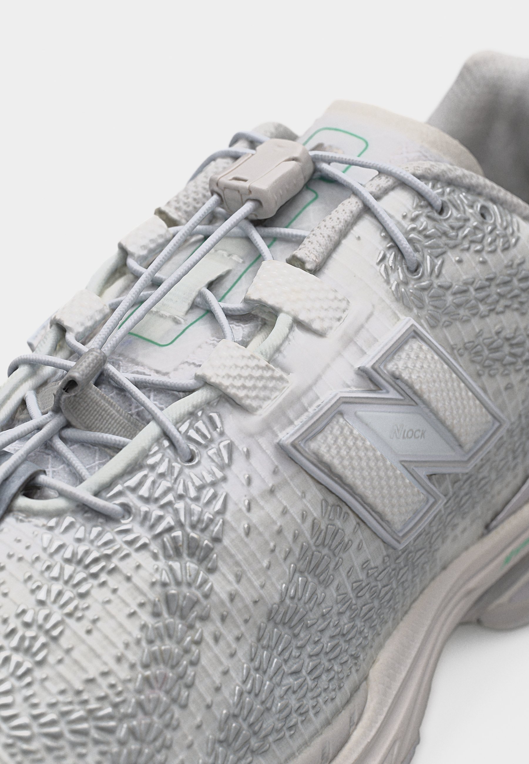 Zapato deportivo blanco con parte superior texturizada, cordones elásticos sin atar asegurados por un taco de plástico y un gran logo "N" en el lateral.