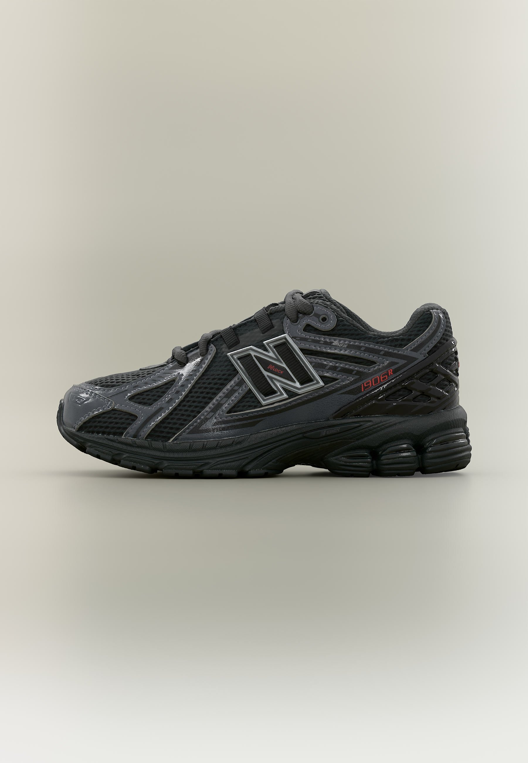 Zapatilla de running New Balance 1906R en negro y gris con materiales de malla y sintéticos, con amortiguación gruesa y cierre con cordones.
