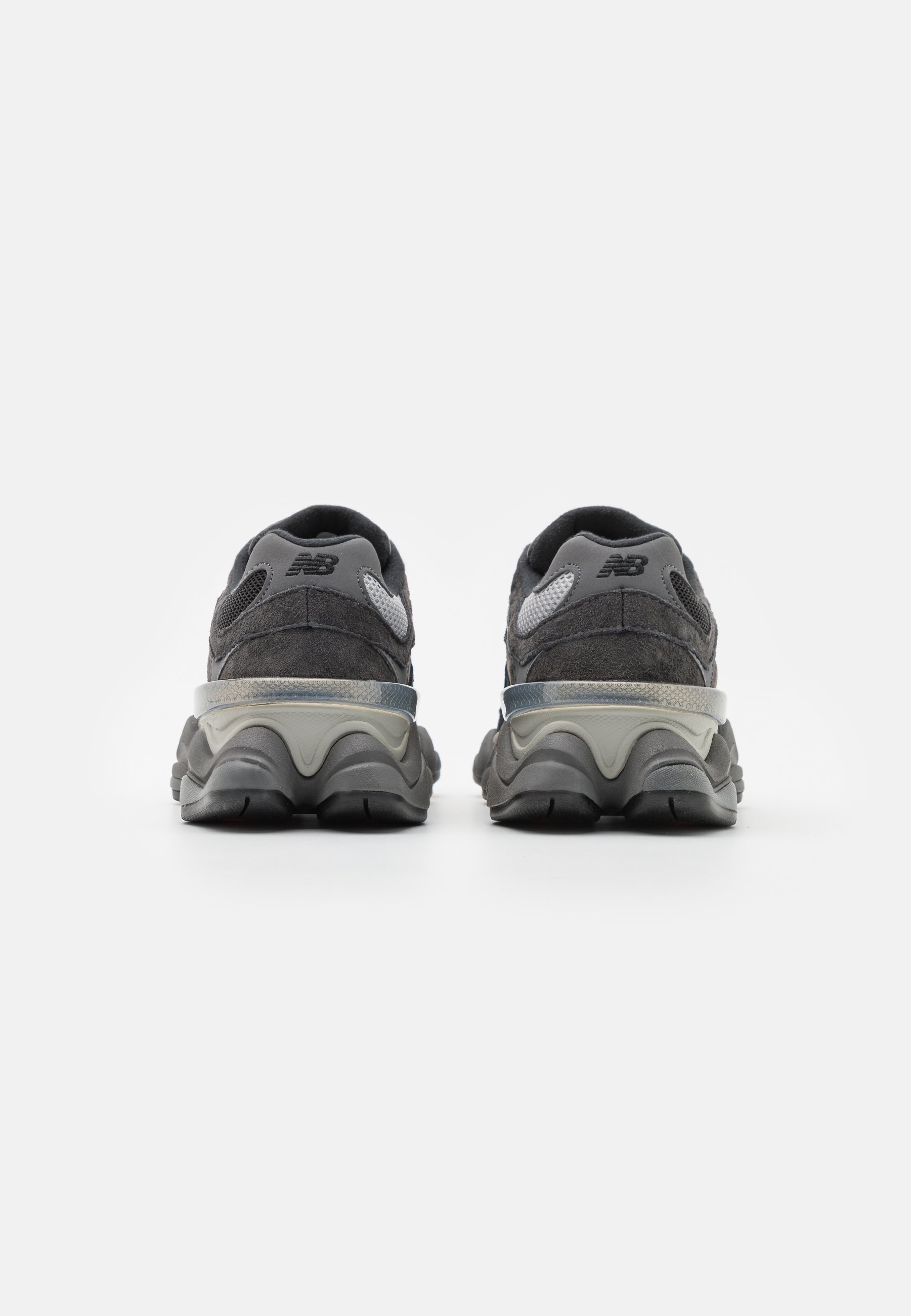 Zapatos deportivos grises con materiales de ante y malla, suela texturizada y tacón de altura media. Acentos grises notables en la parte superior y en el tacón.