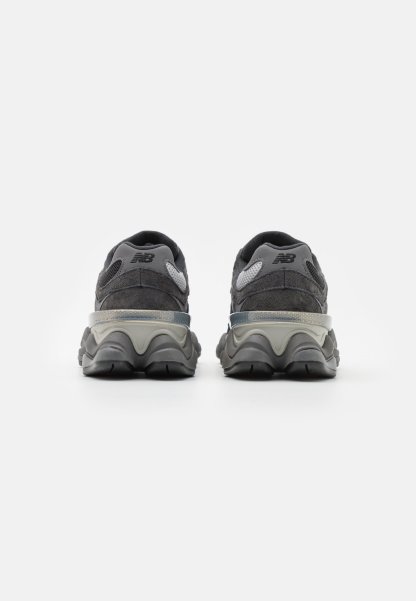 Zapatos deportivos grises con materiales de ante y malla, suela texturizada y tacón de altura media. Acentos grises notables en la parte superior y en el tacón.