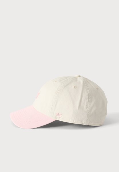 Gorra de béisbol beige claro con una visera curva de color rosa pálido, pequeños detalles bordados en el lateral y orificios de ventilación cosidos.