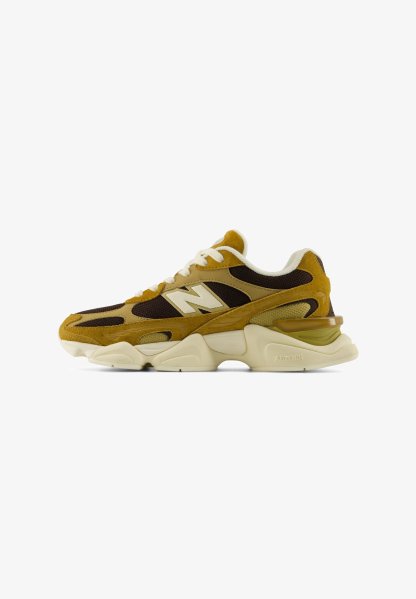 Zapatilla New Balance marrón y beige con cordones blancos y suela beige gruesa diseñada para uso atlético.