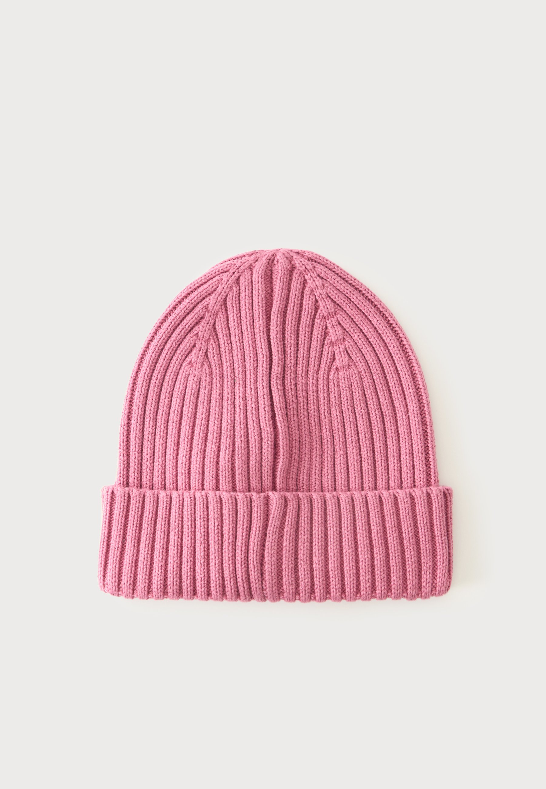 Gorro de punto acanalado rosa con puño doblado mostrado sobre un fondo claro y liso.