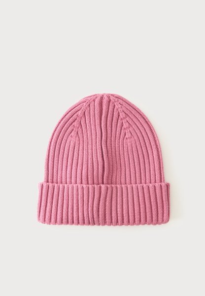 Gorro de punto acanalado rosa con puño doblado mostrado sobre un fondo claro y liso.