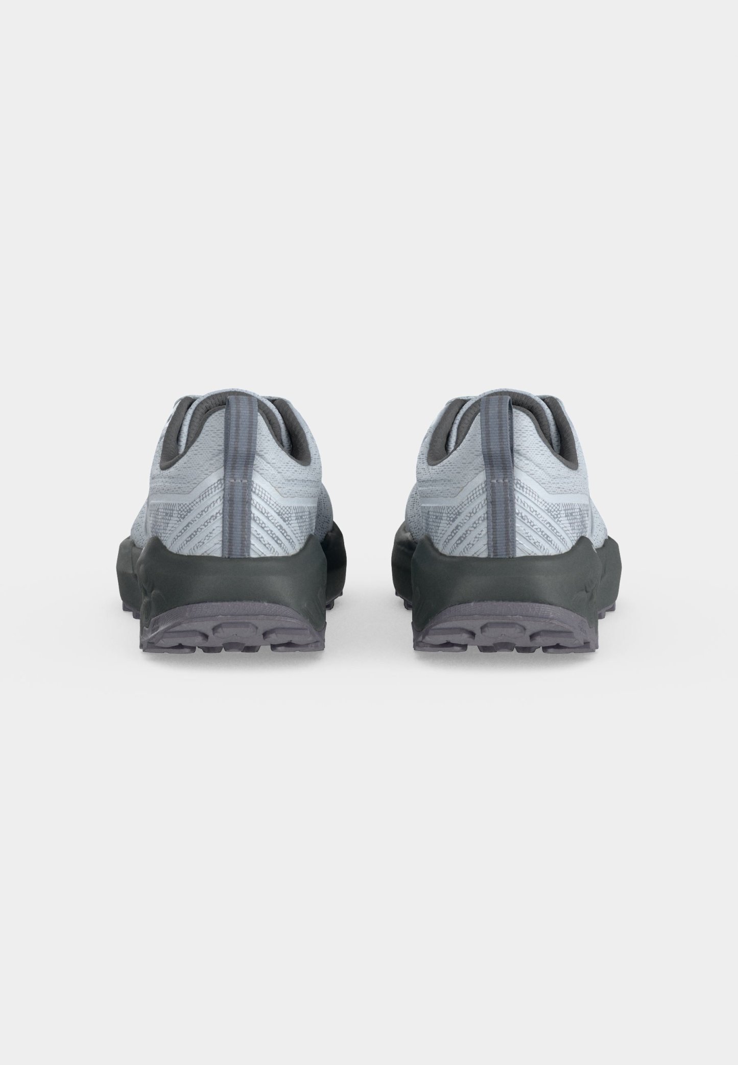 Par de zapatos deportivos grises con partes superiores de tela texturizada y suelas negras gruesas, mostrados desde atrás sobre un fondo blanco liso.