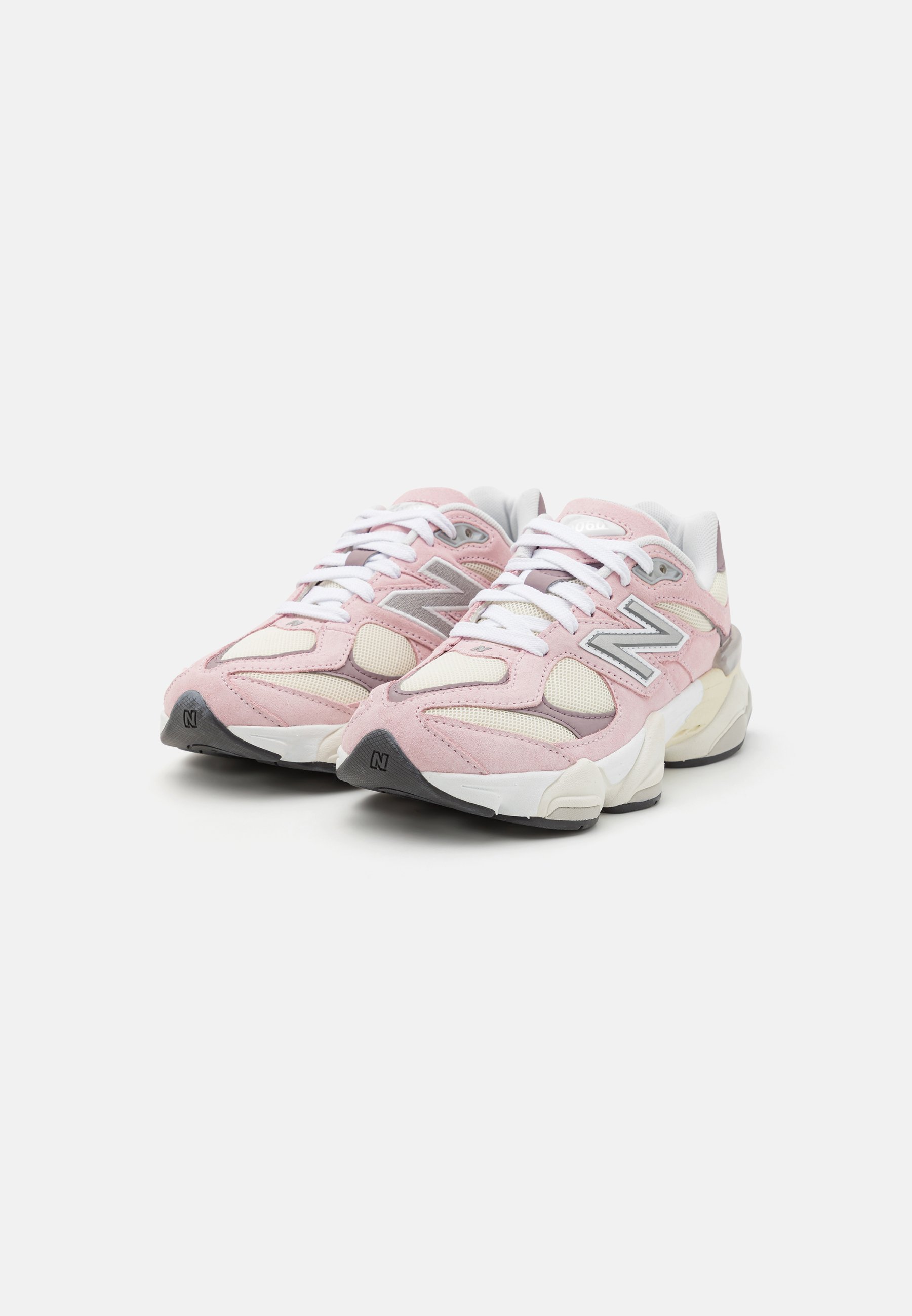 Zapatillas deportivas en color rosa y crema con paneles de ante y malla, que cuentan con una gruesa suela blanca y detalles en gris. Los cordones son blancos y el logo está en el costado.