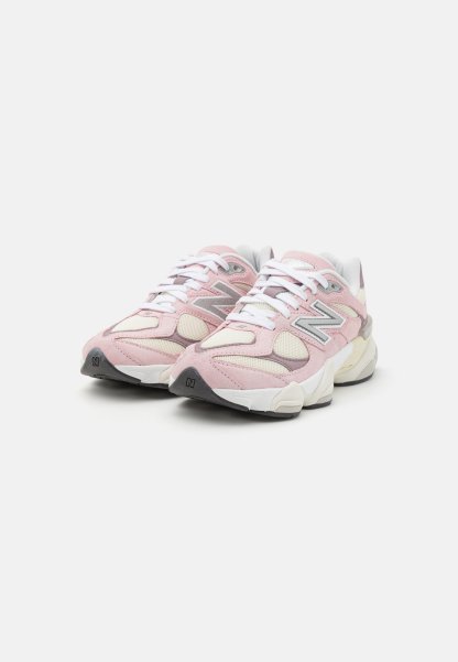Zapatillas deportivas en color rosa y crema con paneles de ante y malla, que cuentan con una gruesa suela blanca y detalles en gris. Los cordones son blancos y el logo está en el costado.