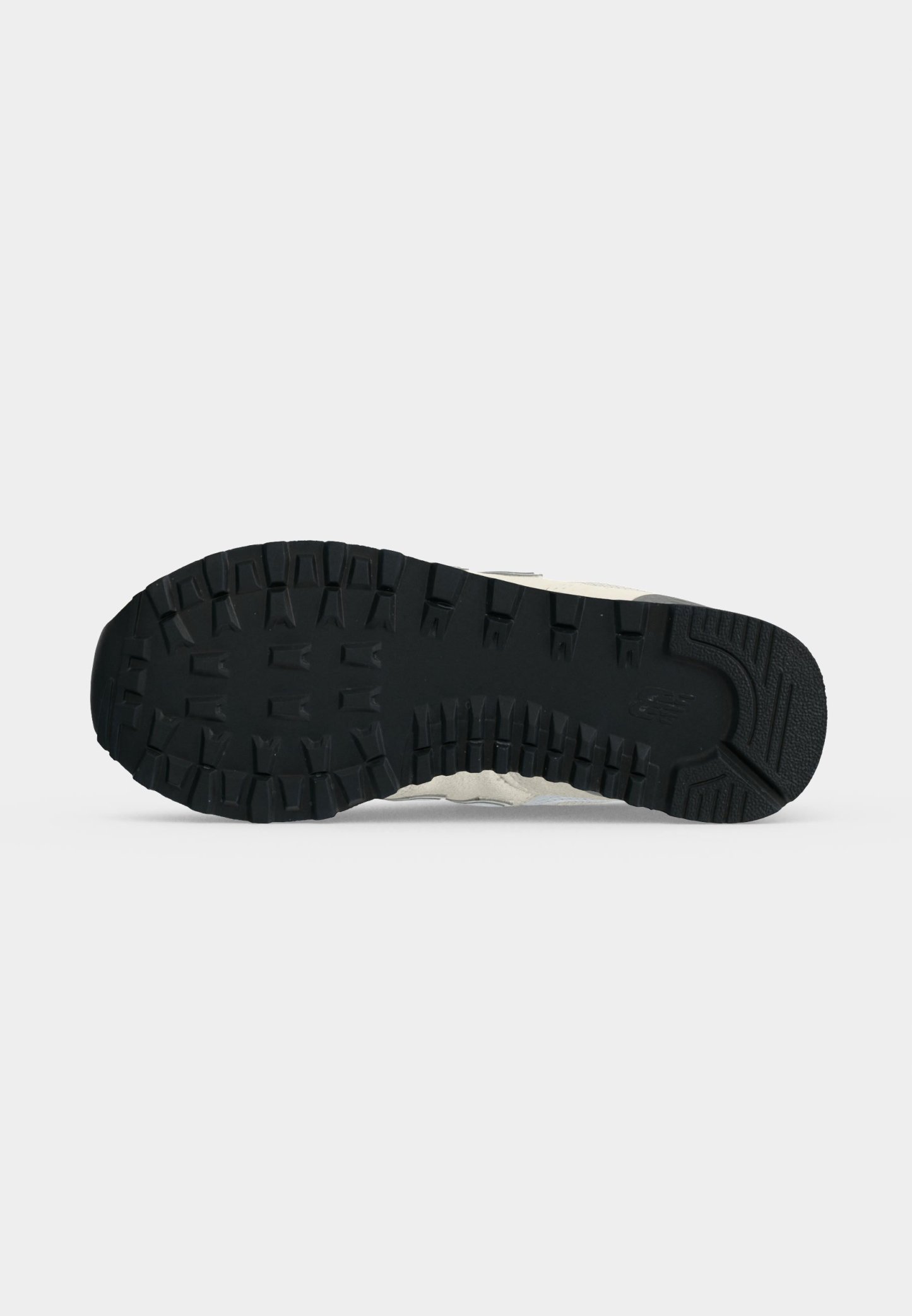 Suela de goma negra de una zapatilla con tacos profundos para tracción, mostrada sobre un fondo claro y liso.