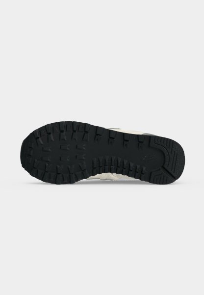 Suela de goma negra de una zapatilla con tacos profundos para tracción, mostrada sobre un fondo claro y liso.