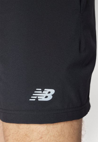 Shorts atléticos negros fabricados con un tejido suave y ligero. Presentan un logo blanco de New Balance cerca del dobladillo y bolsillos laterales.
