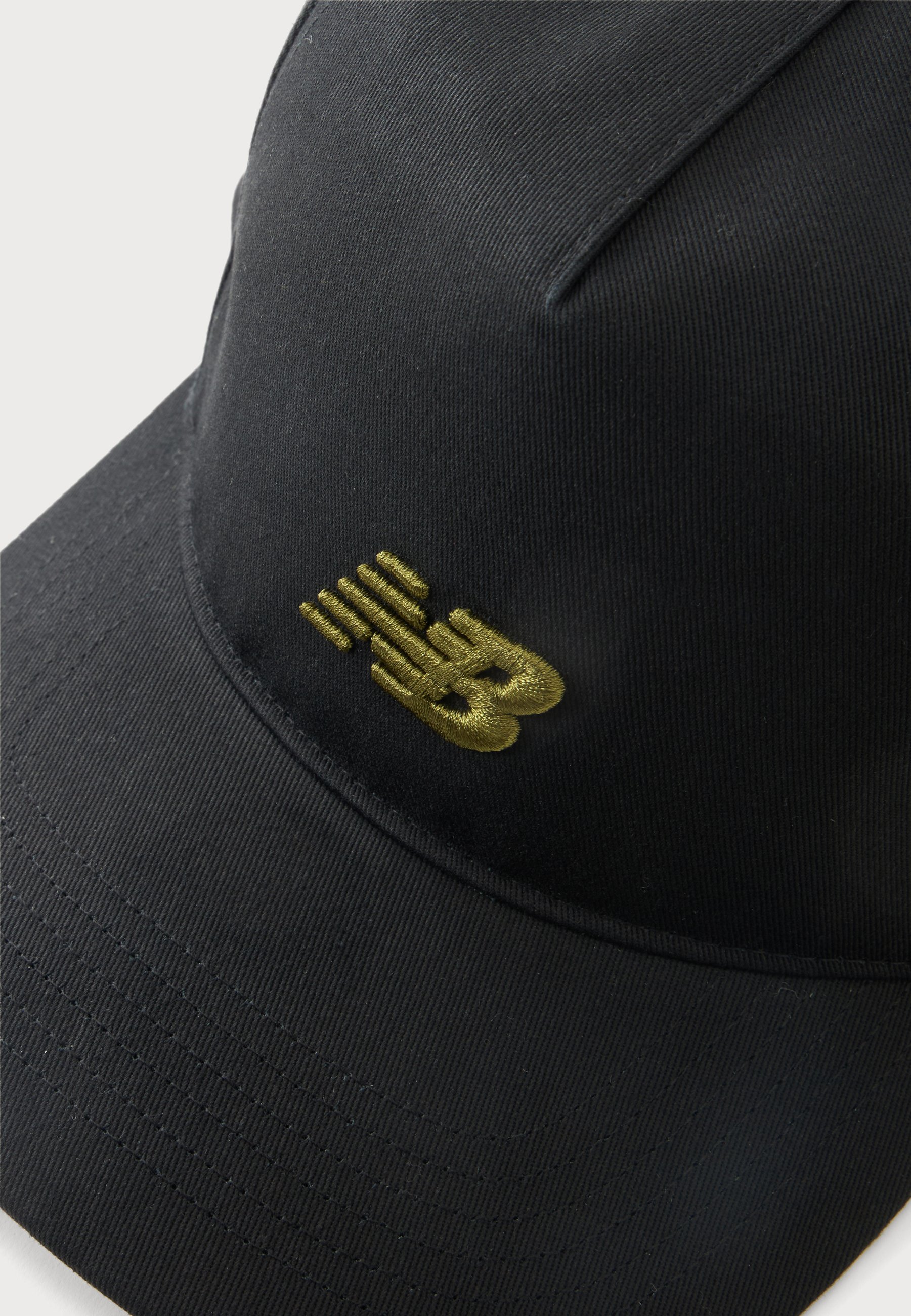 Gorra de béisbol negra con visera curva y un logo "NB" bordado en dorado en el panel frontal.