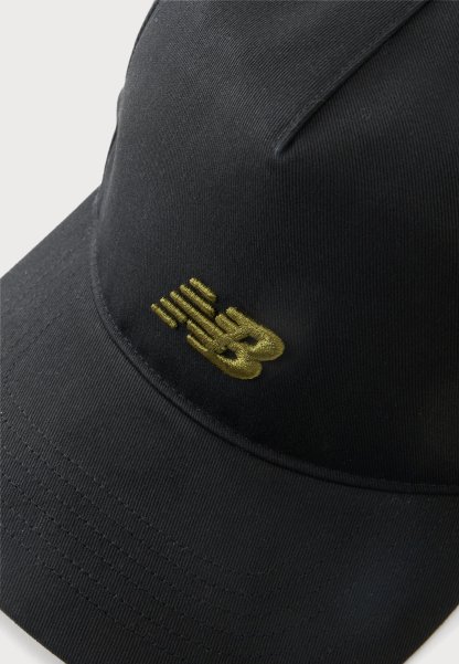Gorra de béisbol negra con visera curva y un logo "NB" bordado en dorado en el panel frontal.