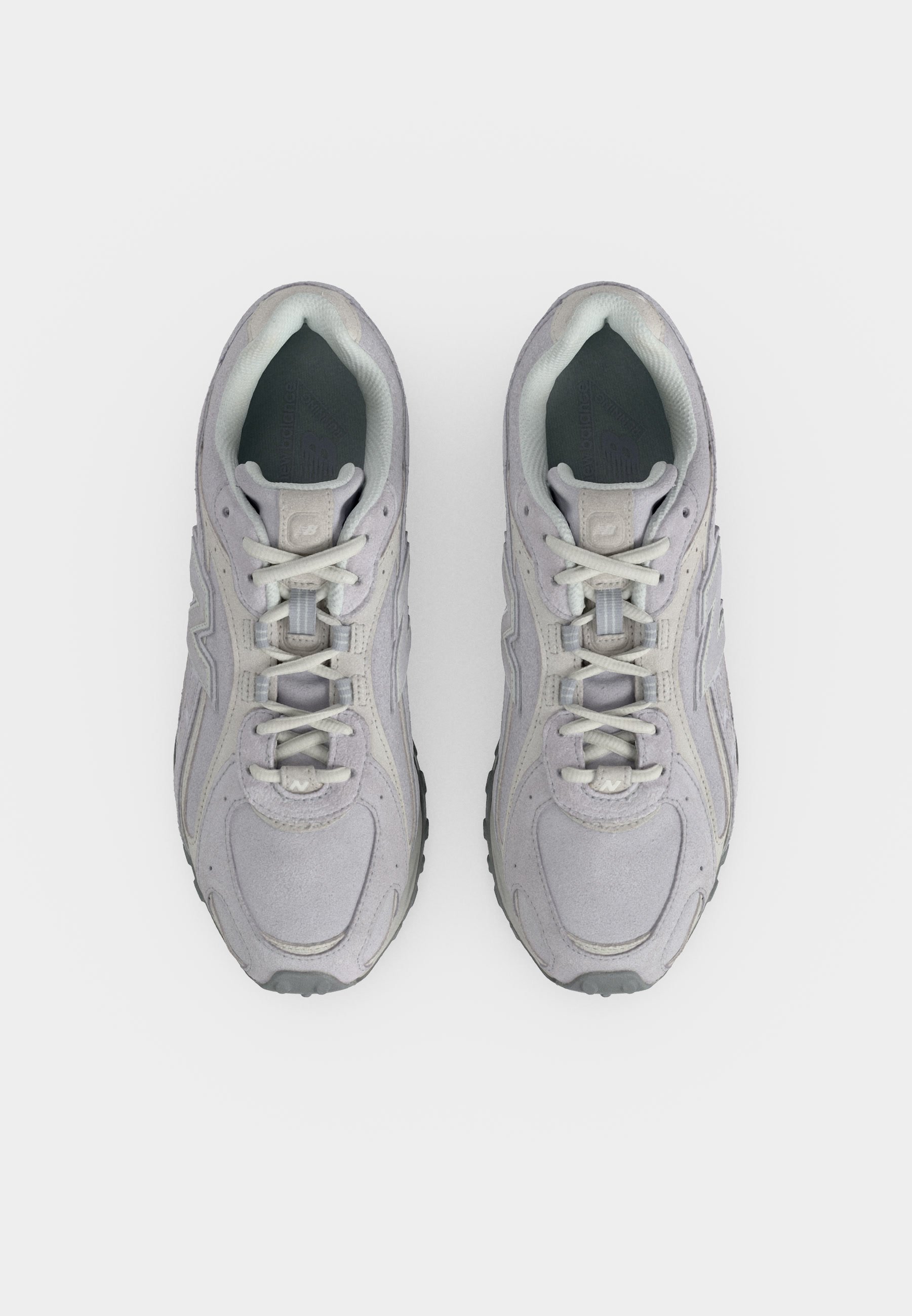 Par de zapatillas deportivas de color gris claro con cordones blancos vistas desde arriba sobre un fondo blanco liso.
