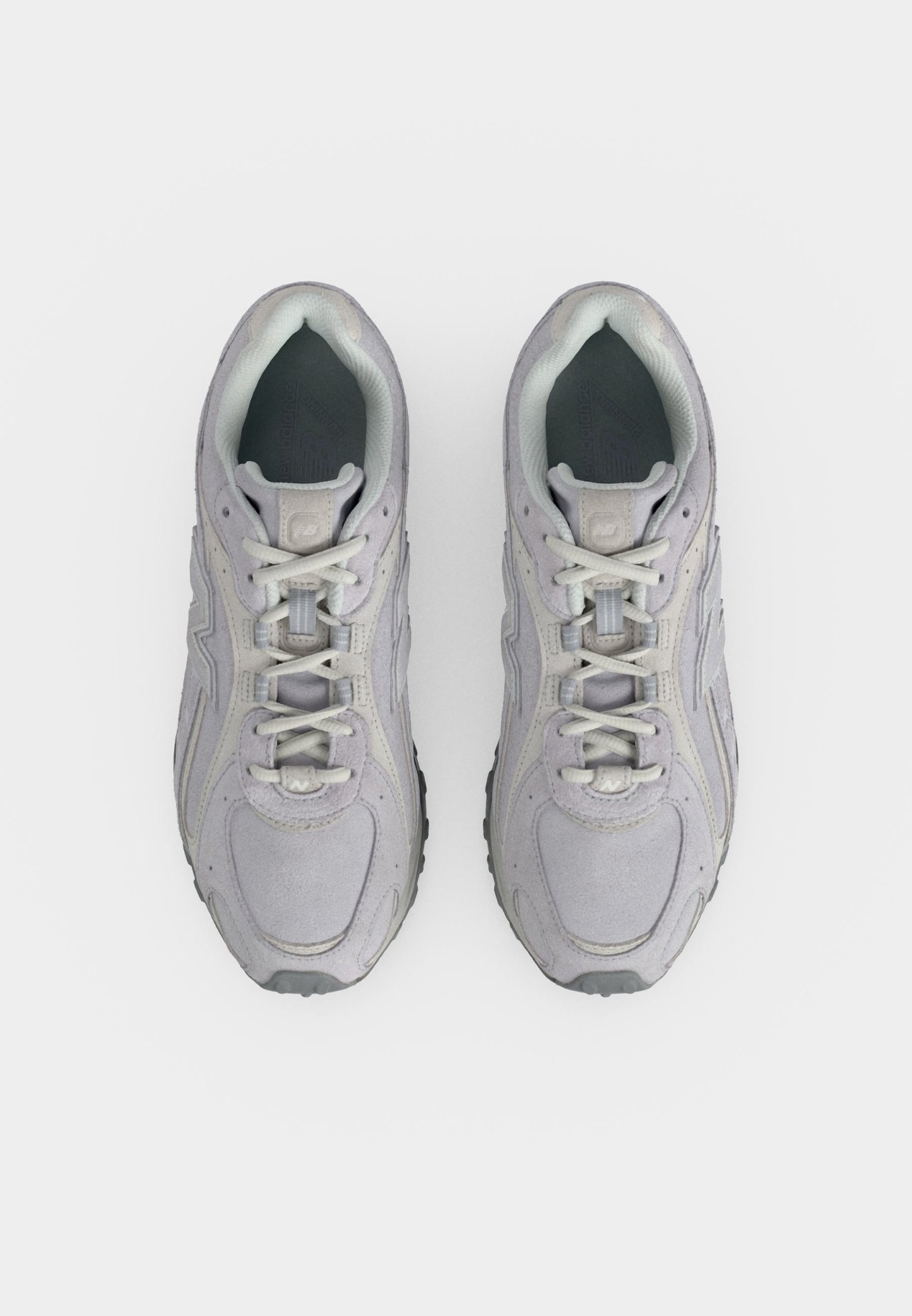 Par de zapatillas deportivas de color gris claro con cordones blancos vistas desde arriba sobre un fondo blanco liso.