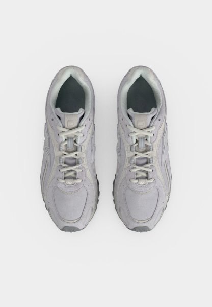 Par de zapatillas deportivas de color gris claro con cordones blancos vistas desde arriba sobre un fondo blanco liso.
