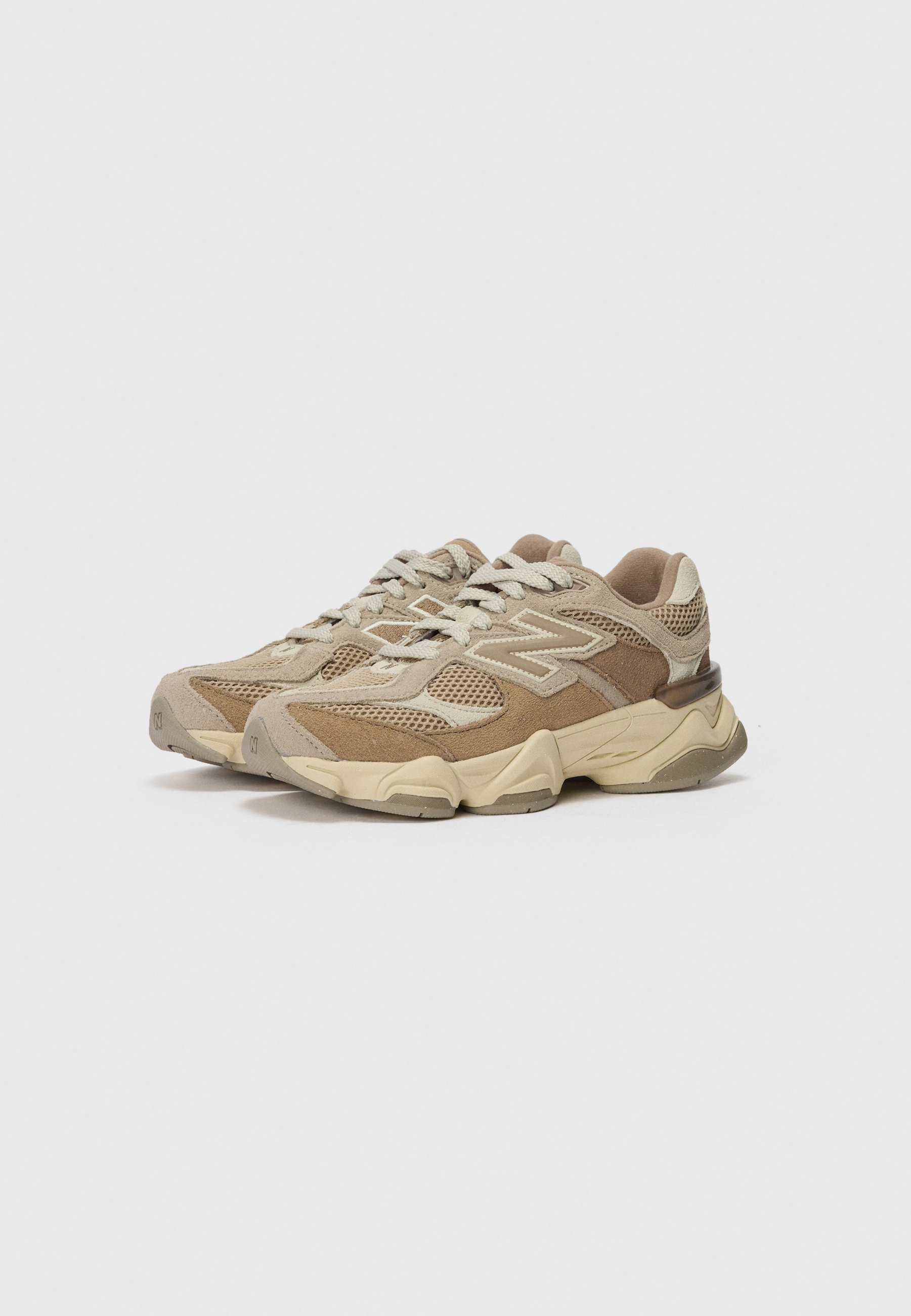 Zapatillas deportivas beige con materiales de malla y ante, acentos texturizados y suela de goma gruesa. Presentan cordones en contraste y detalle de logo.