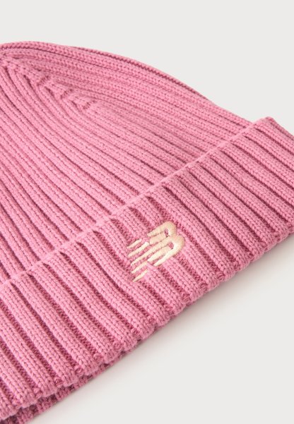 Gorro de punto acanalado rosa con puño doblado y pequeño logo bordado en rosa claro en el puño sobre un fondo blanco.