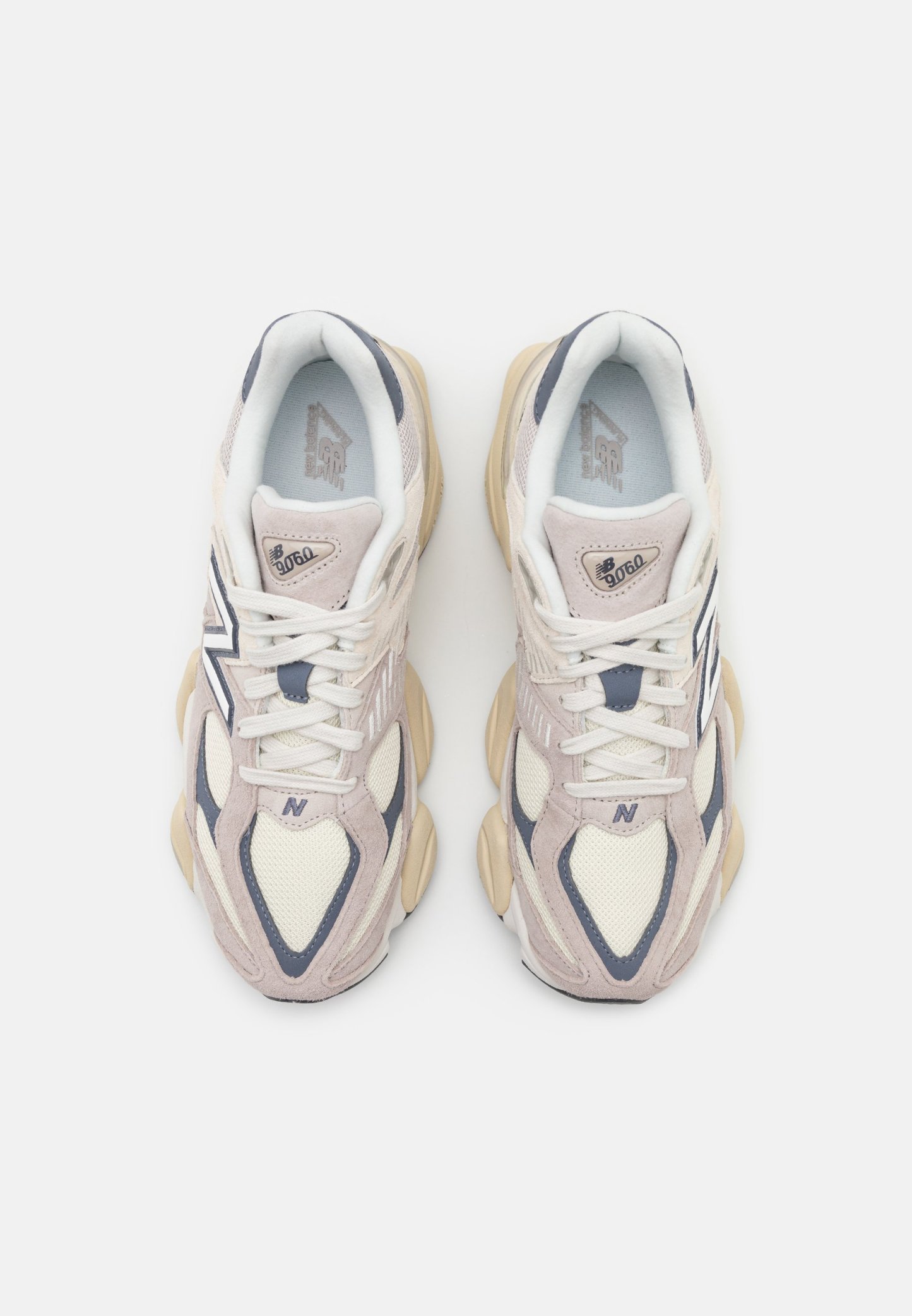 Zapatillas deportivas en beige y gris con texturas de malla y ante, suelas gruesas y un prominente logotipo "N" en el lateral.