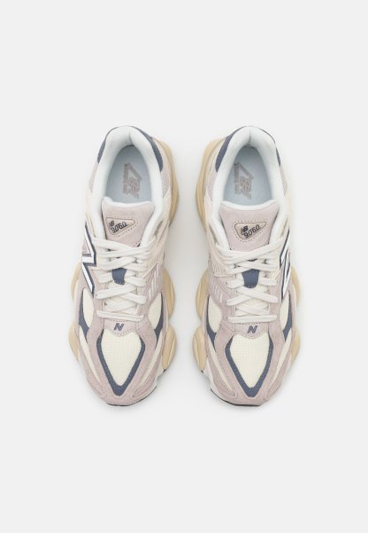Zapatillas deportivas en beige y gris con texturas de malla y ante, suelas gruesas y un prominente logotipo "N" en el lateral.