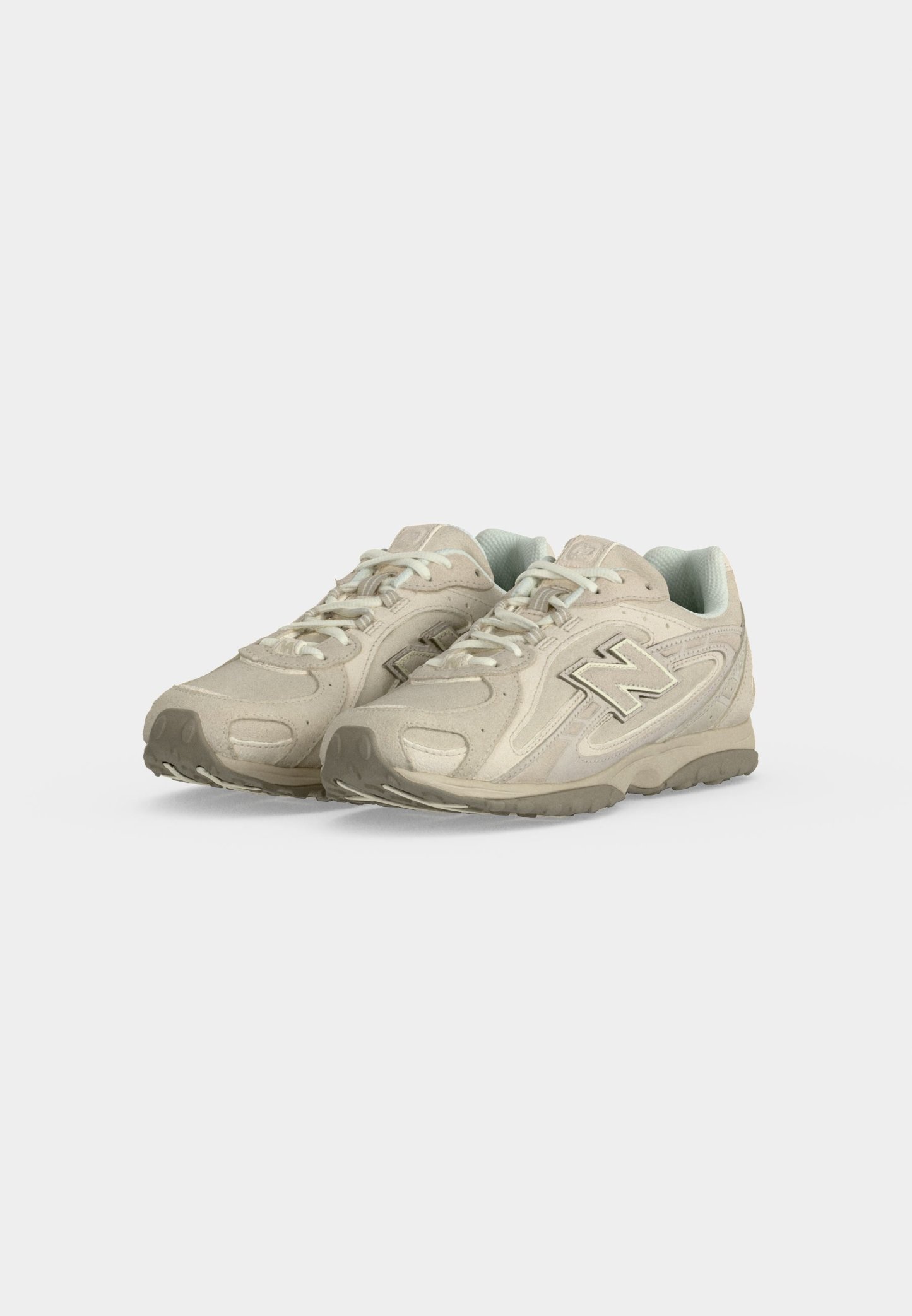 Par de zapatillas New Balance beige con cordones blancos y detalles grises, colocadas una al lado de la otra sobre un fondo blanco.