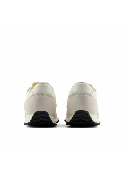 Par de zapatillas beige y blancas vistas desde atrás, con suelas de goma negras con un patrón ondulado y detalle de ante en el talón.
