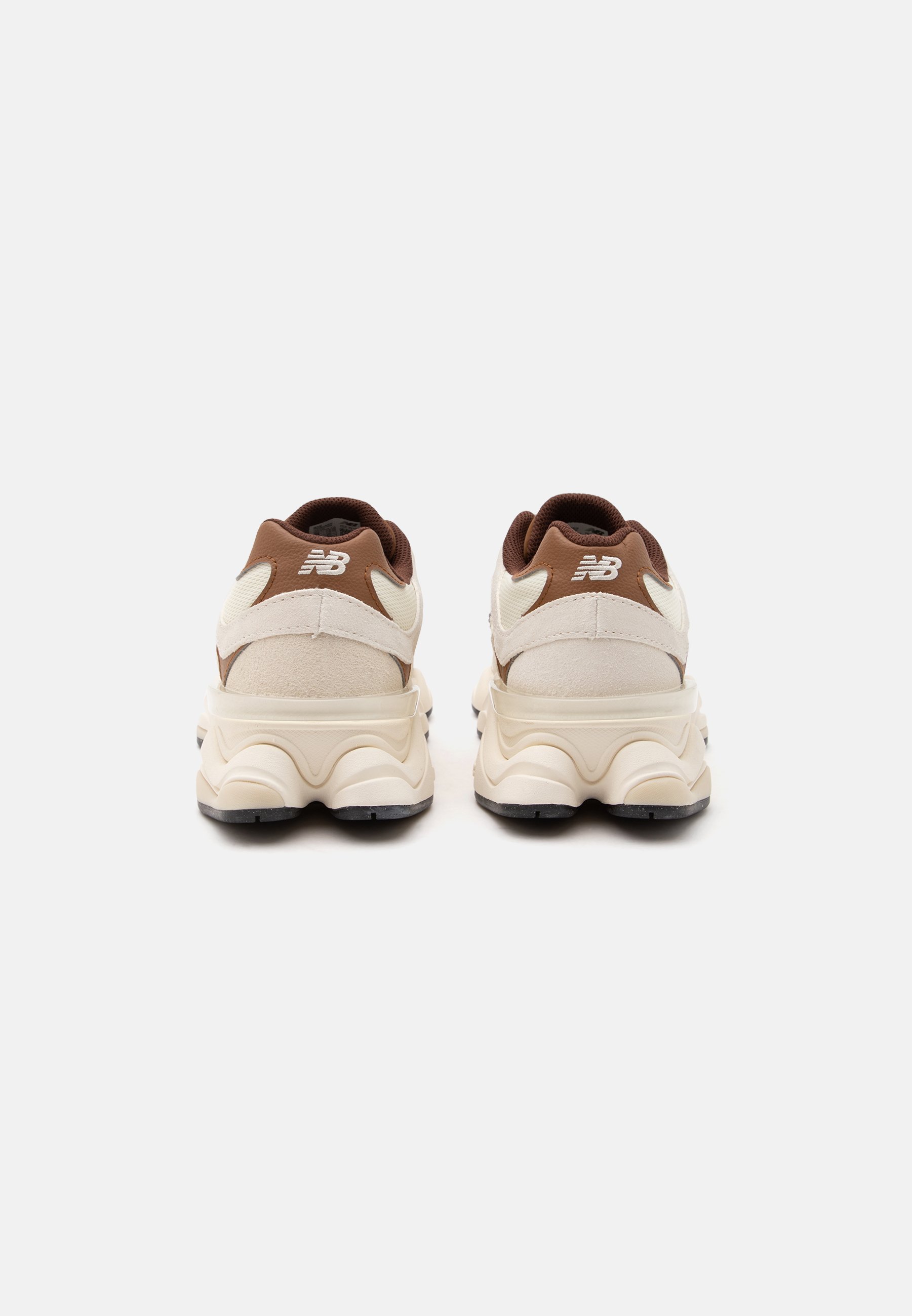 Par de zapatillas New Balance beige y marrón vistas desde atrás sobre un fondo blanco.