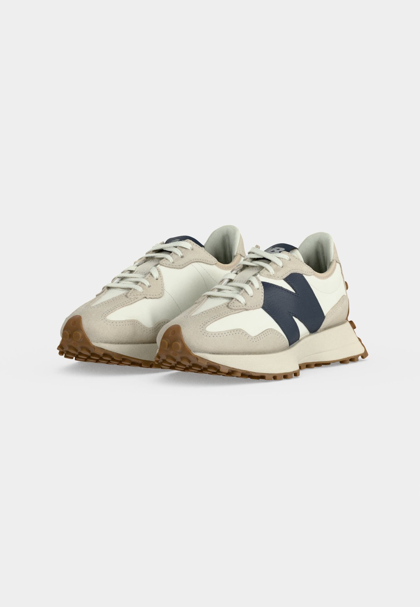 Par de zapatillas beige y blancas con acentos azul marino, cordones blancos y suelas marrones texturizadas sobre un fondo liso gris claro.