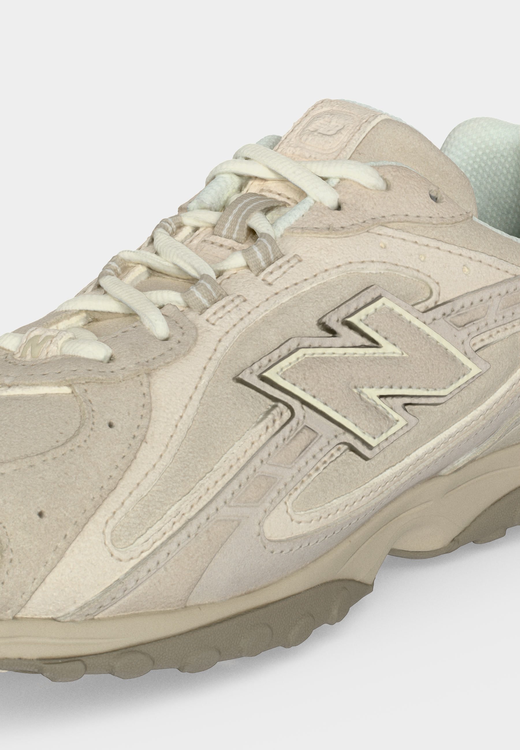 Zapatilla beige y gris claro de ante y malla con cordones crema y un gran logo "N" bordado en el lateral.