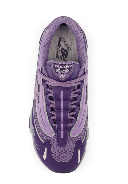 Zapatilla de running morada con materiales de malla y sintéticos, que presenta cordones prominentes, lengüeta acolchada y un diseño en capas con detalles en gris.