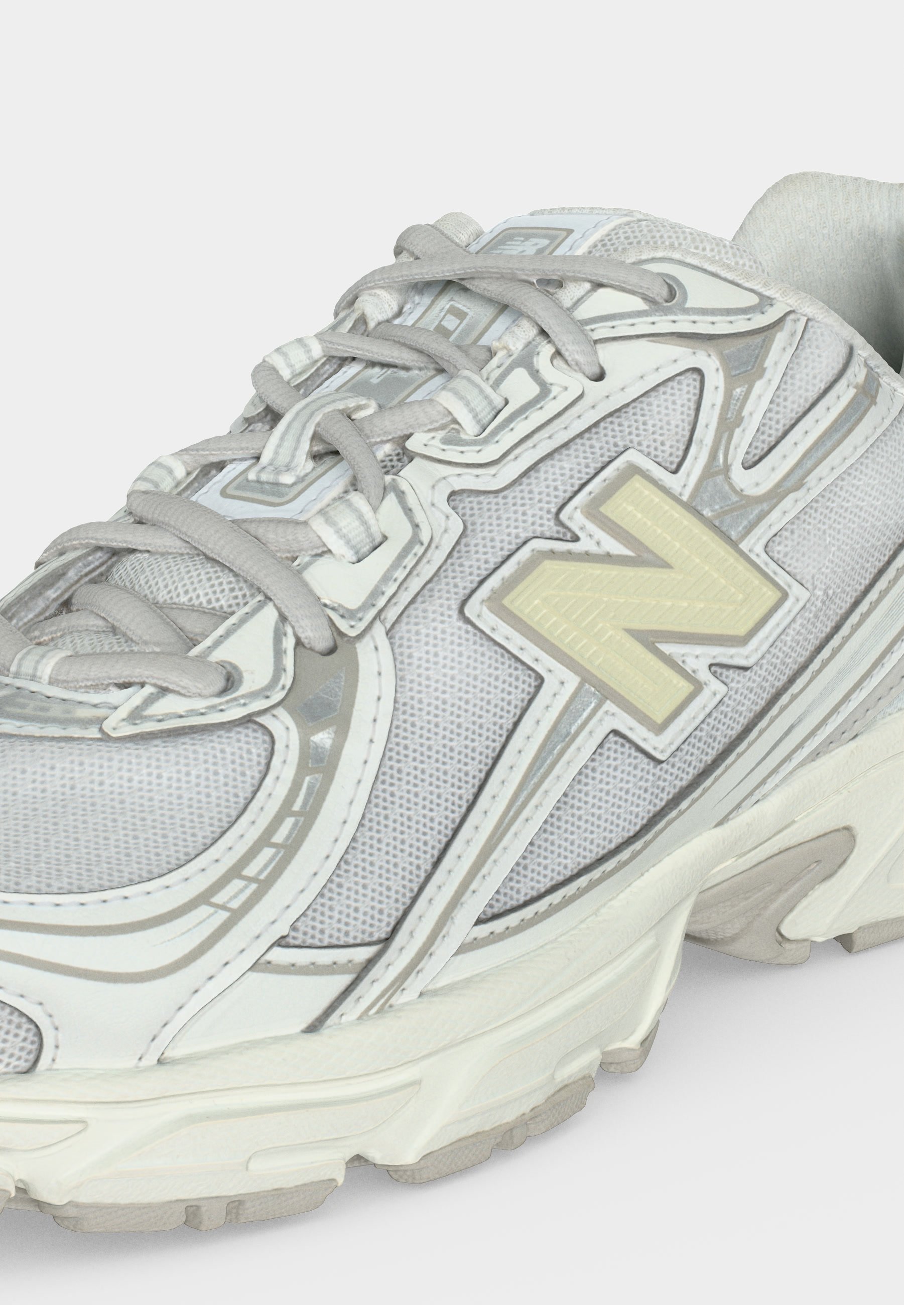 Zapatilla deportiva blanca y gris con tejido de malla, cierre con cordones y gran logo "N" en el lateral.