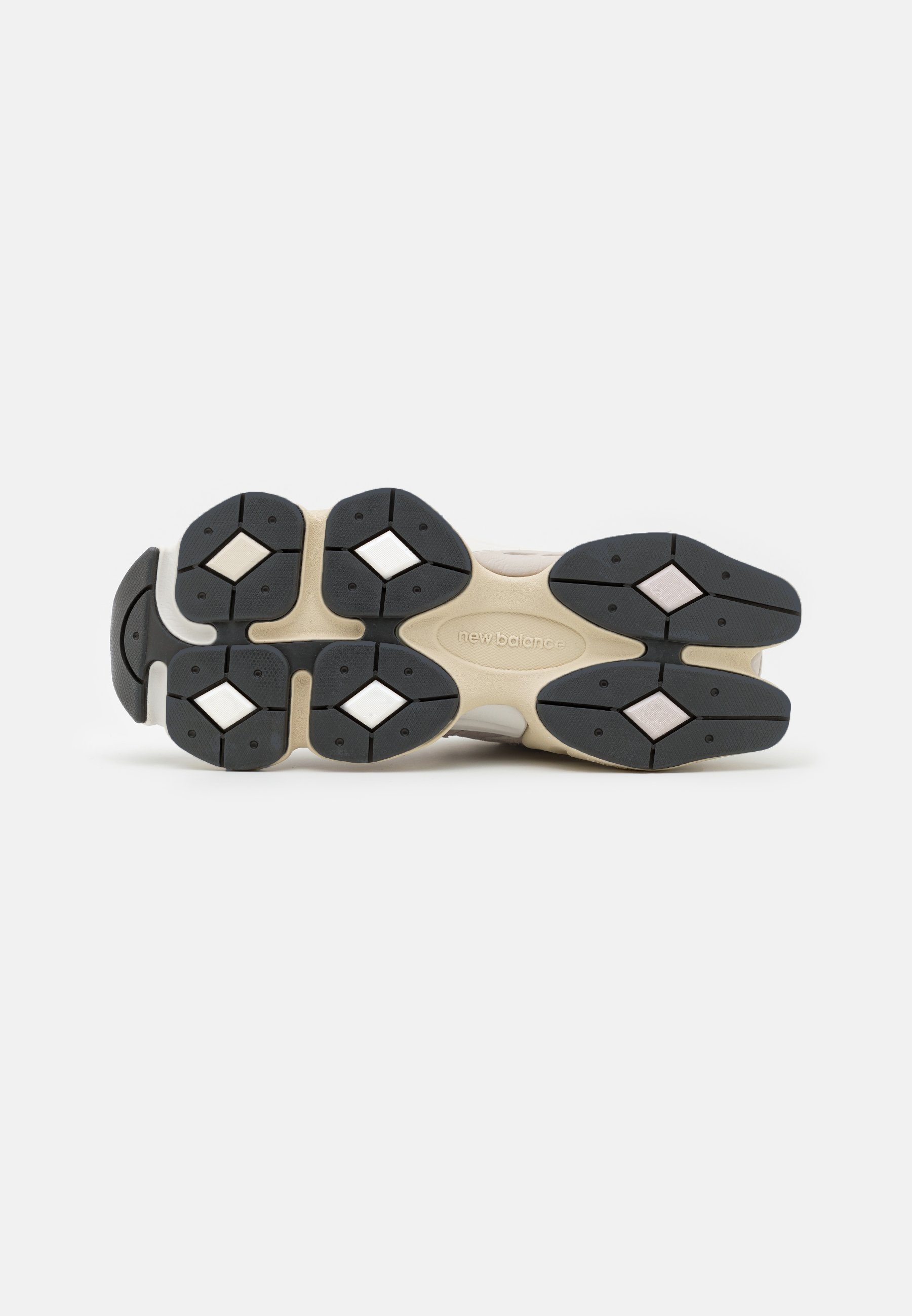 Suela de calzado con un patrón de tracción de goma negra, entresuela beige claro y acentos hexagonales. La textura es suave, con colores contrastantes.
