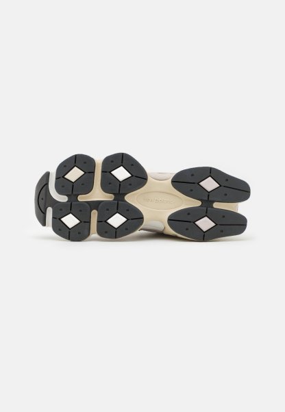 Suela de calzado con un patrón de tracción de goma negra, entresuela beige claro y acentos hexagonales. La textura es suave, con colores contrastantes.