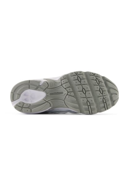 Suela de zapatilla gris y blanca con goma texturizada para tracción. Presenta surcos y patrones circulares, con la marca "newbalance" en el centro.