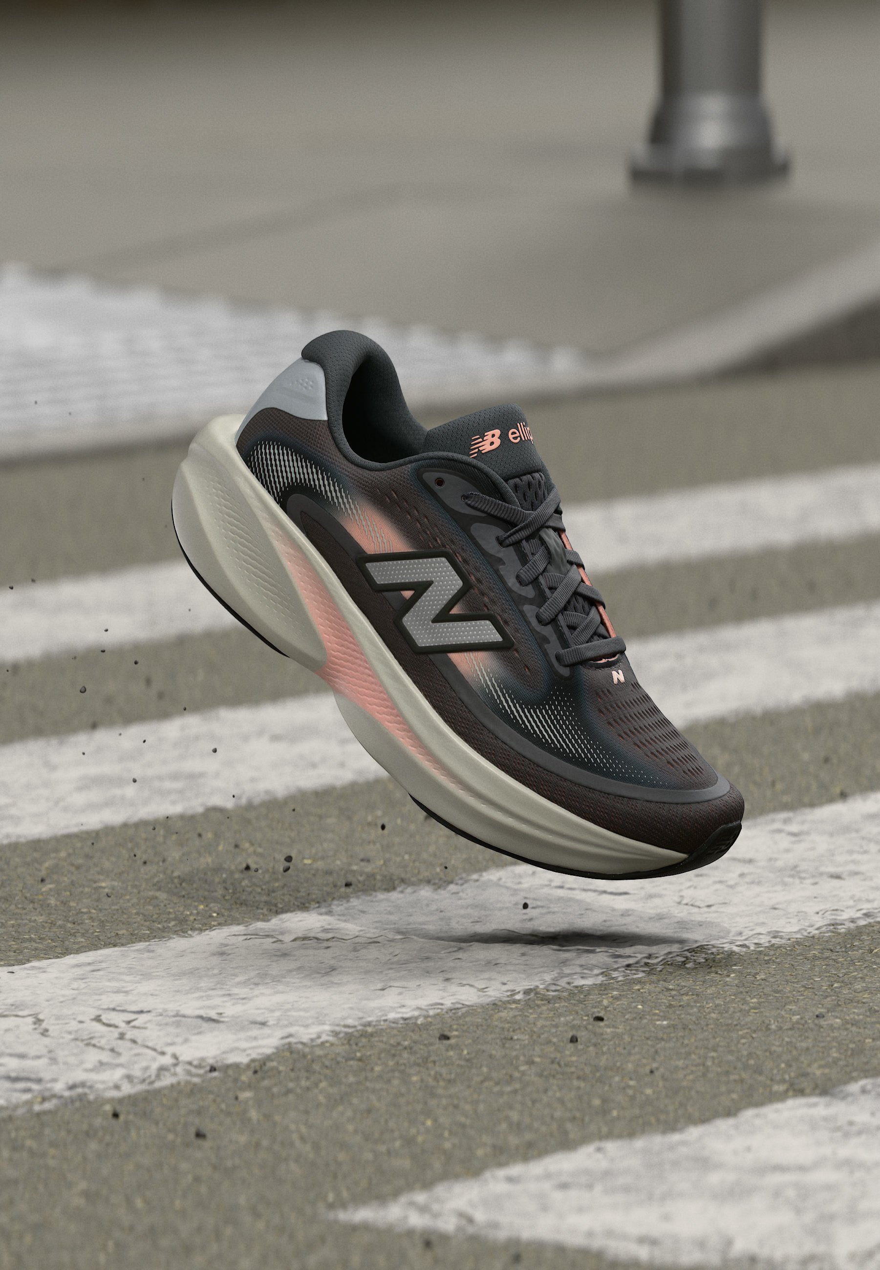 Zapatilla de correr New Balance en negro y gris con detalles en rosa flotando sobre un paso de peatones en una calle urbana.