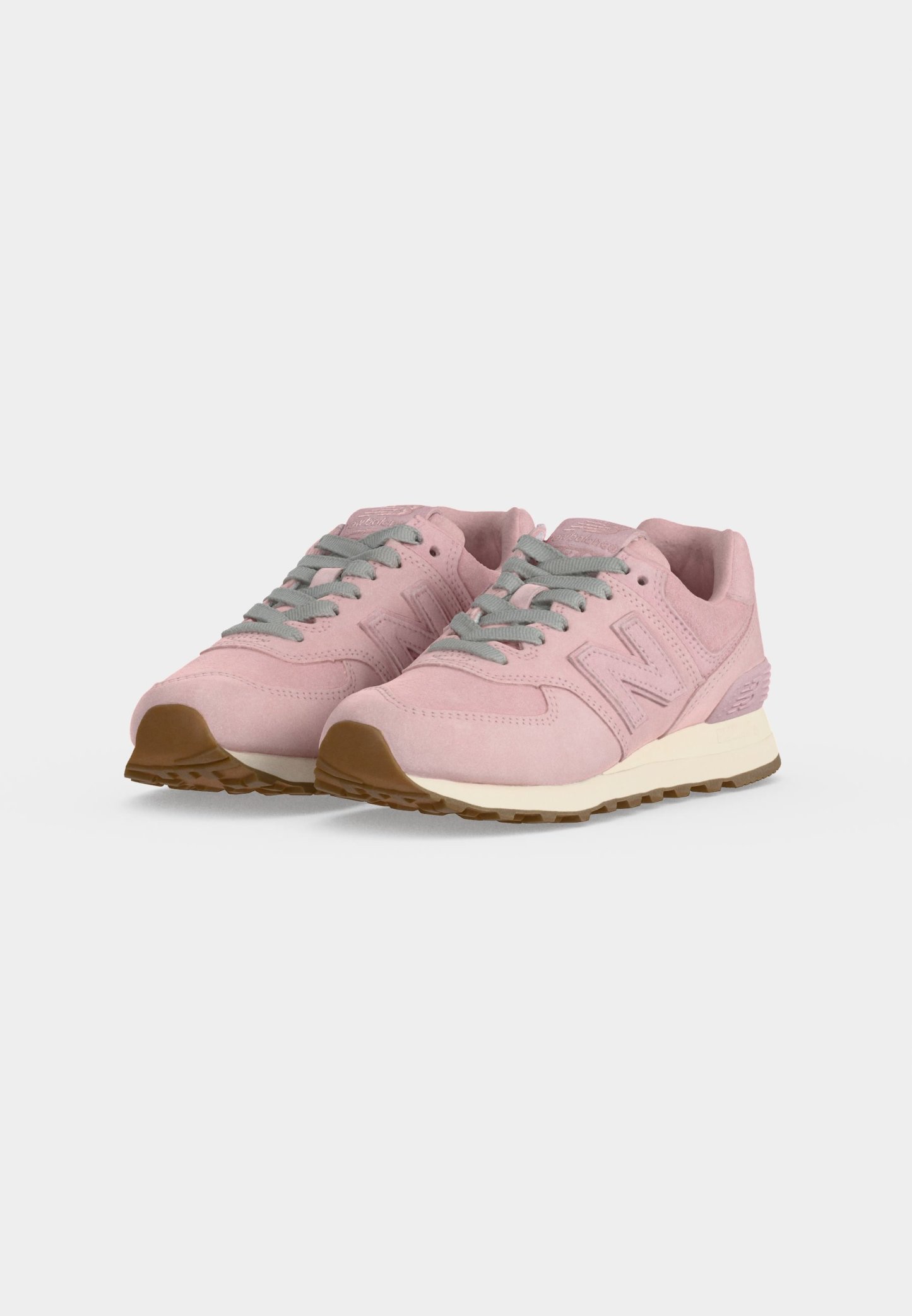 Par de zapatillas de gamuza rosa con cordones grises y suelas de goma marrones sobre un fondo liso y claro.