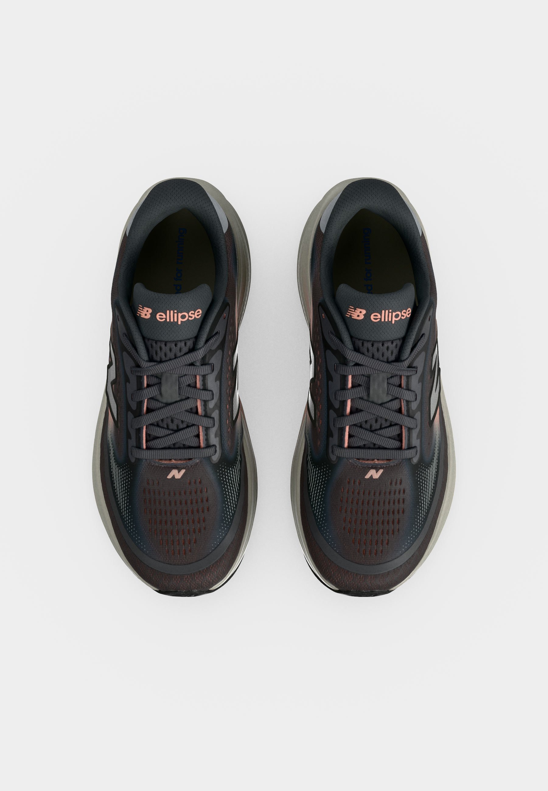 Par de zapatillas de running New Balance en gris oscuro y negro con detalles rosas y la marca "ellipse" en las lengüetas, vistas desde arriba sobre fondo blanco.