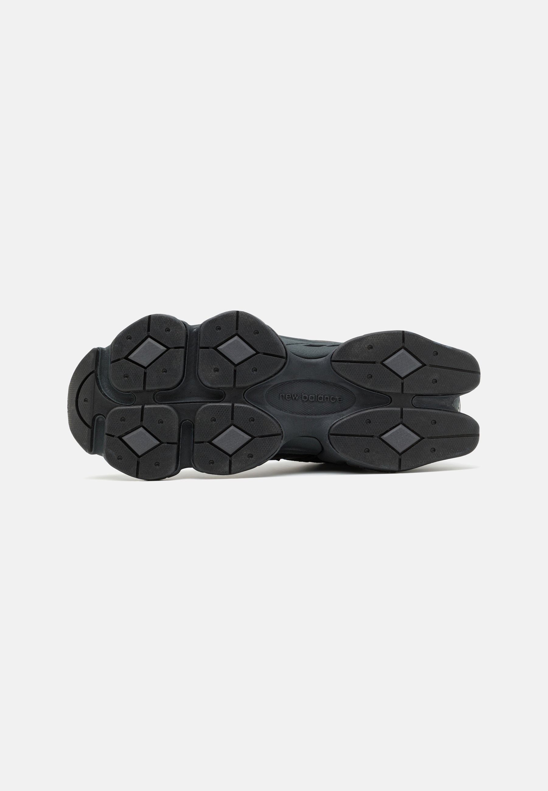 Suela de zapatilla negra con caucho texturizado, con patrones geométricos y un logotipo de marca prominente. Diseñada para ofrecer agarre y durabilidad.
