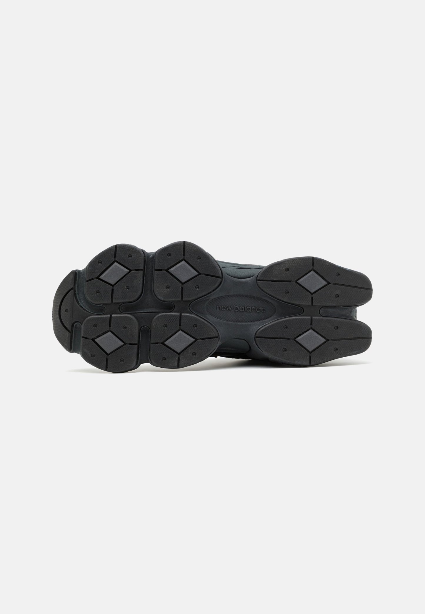 Suela de zapatilla negra con caucho texturizado, con patrones geométricos y un logotipo de marca prominente. Diseñada para ofrecer agarre y durabilidad.