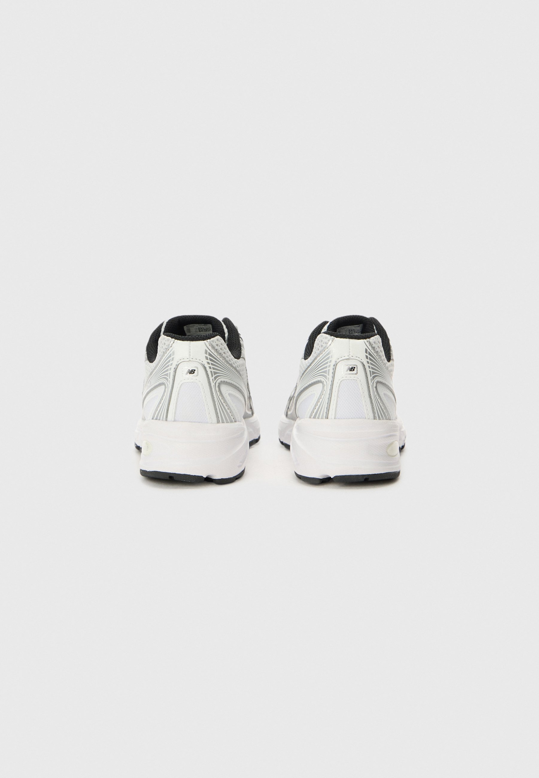 Par de zapatillas de correr blancas y grises con forro interior negro, vistas desde atrás sobre un fondo liso de color gris claro.