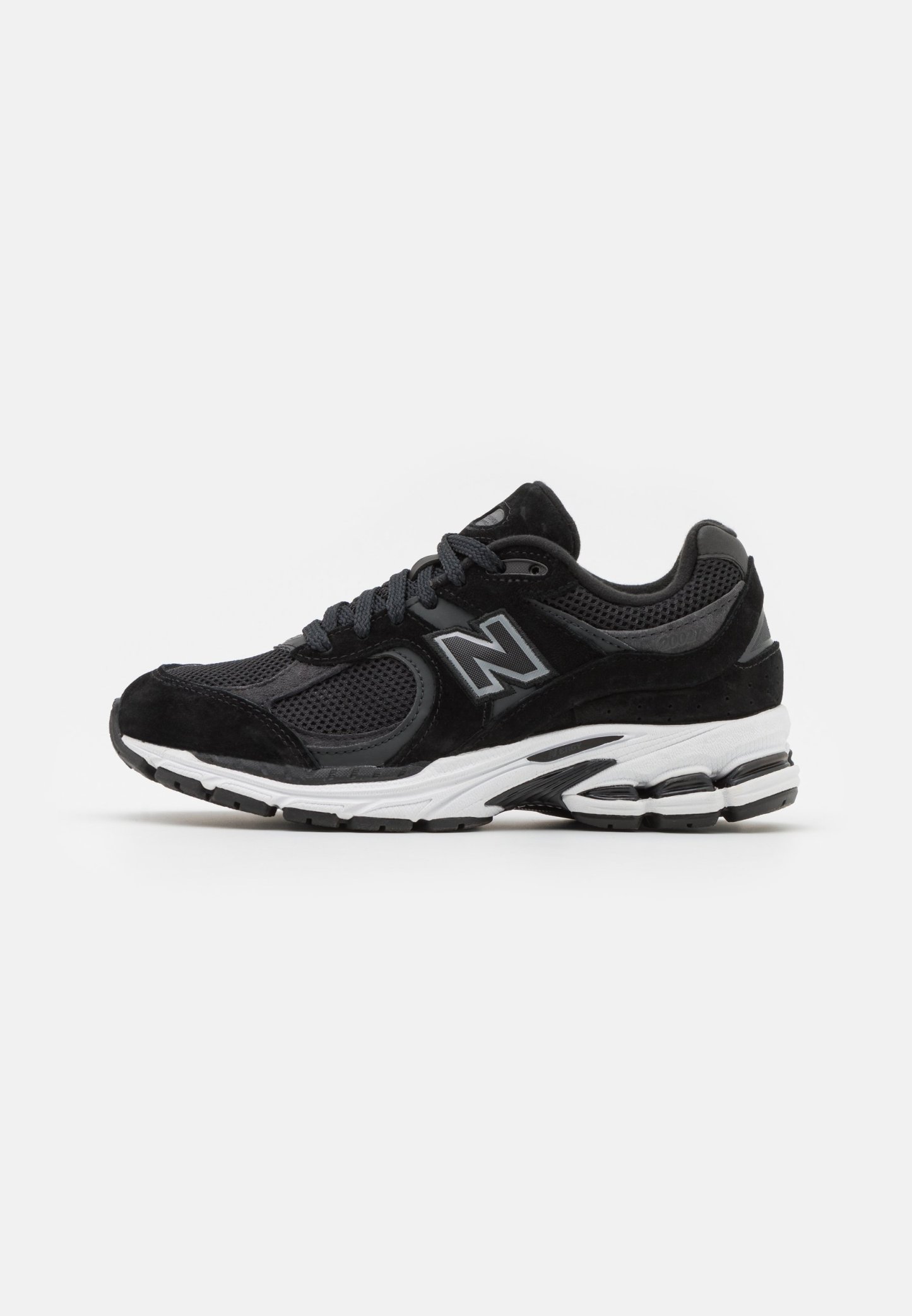 Zapatilla deportiva negra con una parte superior de malla, detalles en ante y una suela blanca texturizada con un pequeño tacón. Incluye cordones negros y un detalle del logotipo.