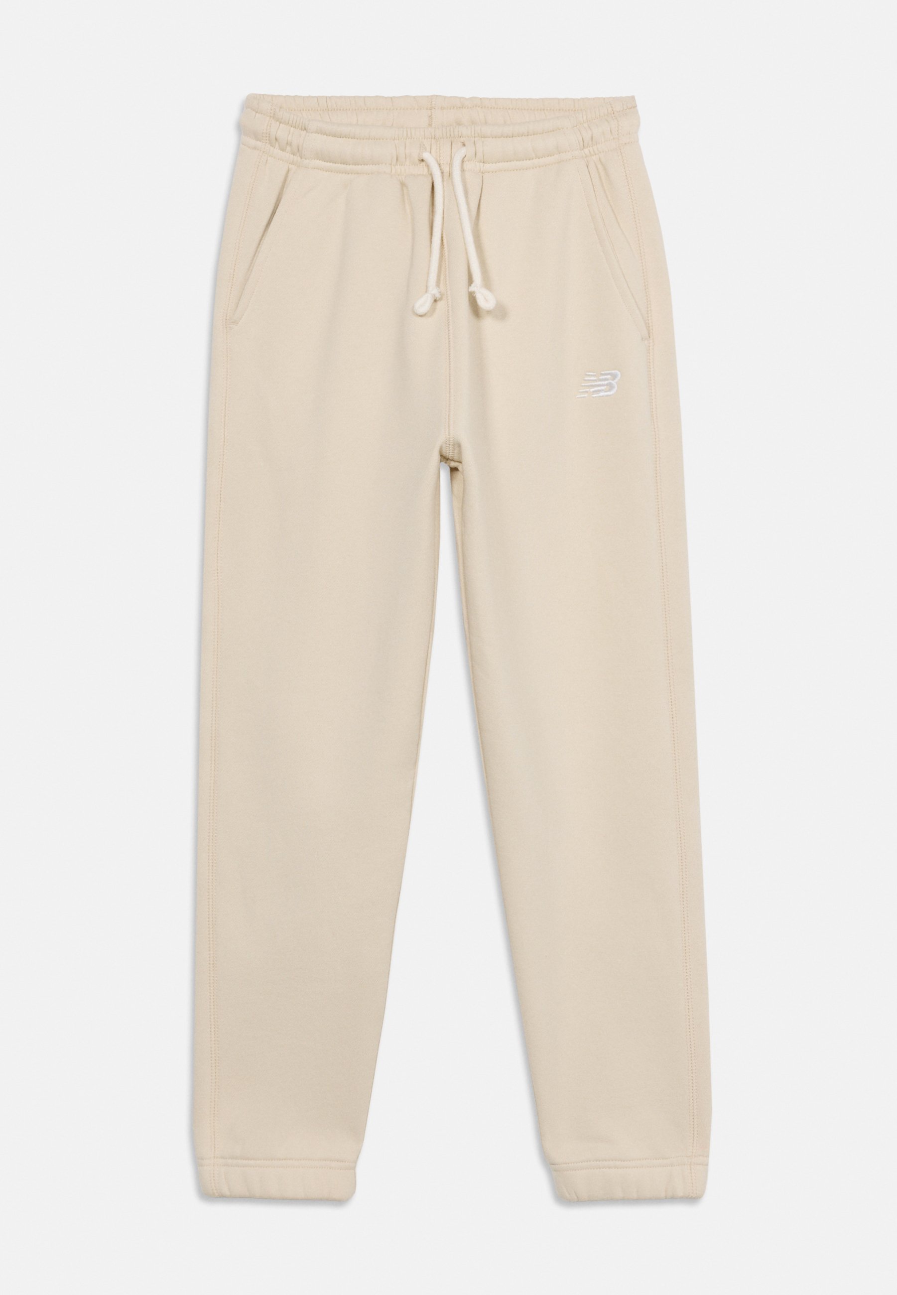 Pantalones jogger de color beige claro con cintura elástica, cordón ajustable, bolsillos laterales y un pequeño logo blanco en el muslo derecho.