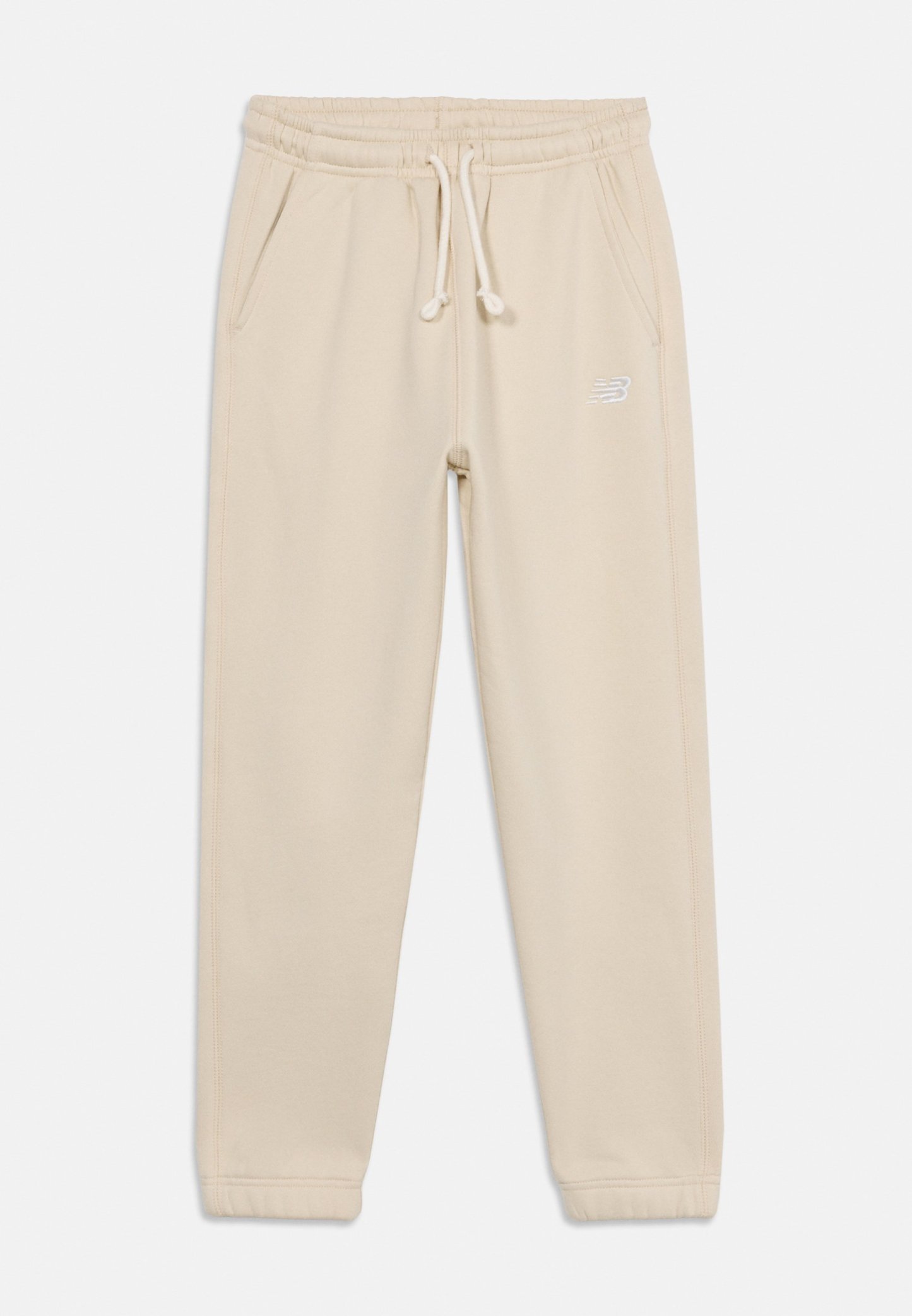 Pantalones jogger de color beige claro con cintura elástica, cordón ajustable, bolsillos laterales y un pequeño logo blanco en el muslo derecho.