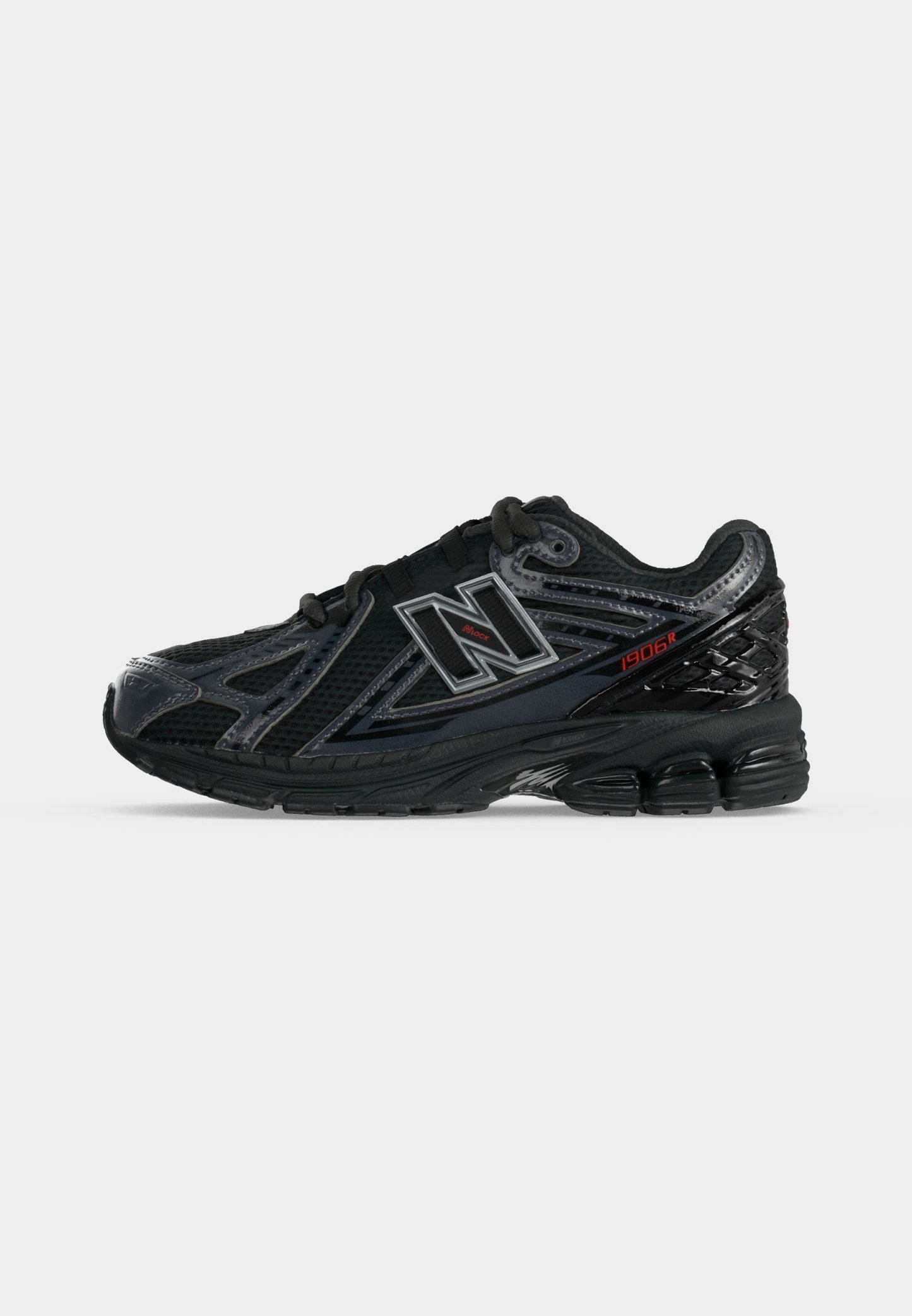 Zapatilla negra New Balance 1906R con malla y superposiciones sintéticas, suela acolchada y detalles reflectantes sobre fondo blanco.
