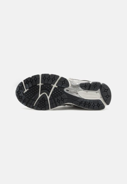 Suela de goma negra con patrones texturizados, silueta curvada y acentos en blanco y gris a lo largo del costado para mayor estabilidad y agarre.