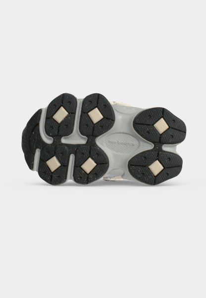 Suela de un zapato New Balance con almohadillas de tracción de goma negra e insertos acolchados beige en forma de diamante sobre fondo blanco.