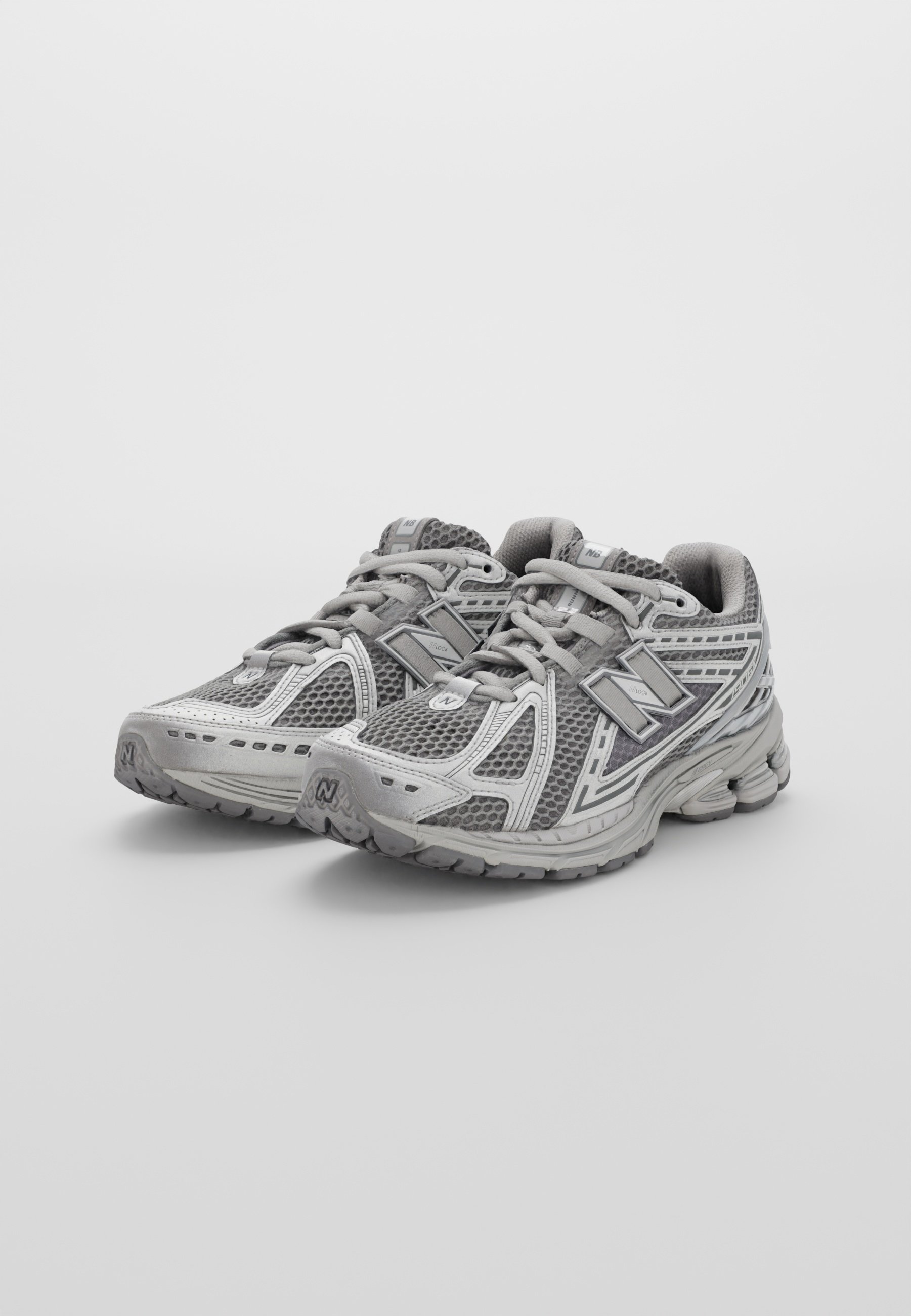 Zapatillas deportivas grises con parte superior de malla, puntera reforzada y suela texturizada. Con detalles reflectantes y cuello acolchado para mayor comodidad.