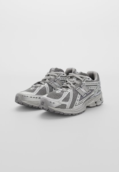 Zapatillas deportivas grises con parte superior de malla, puntera reforzada y suela texturizada. Con detalles reflectantes y cuello acolchado para mayor comodidad.