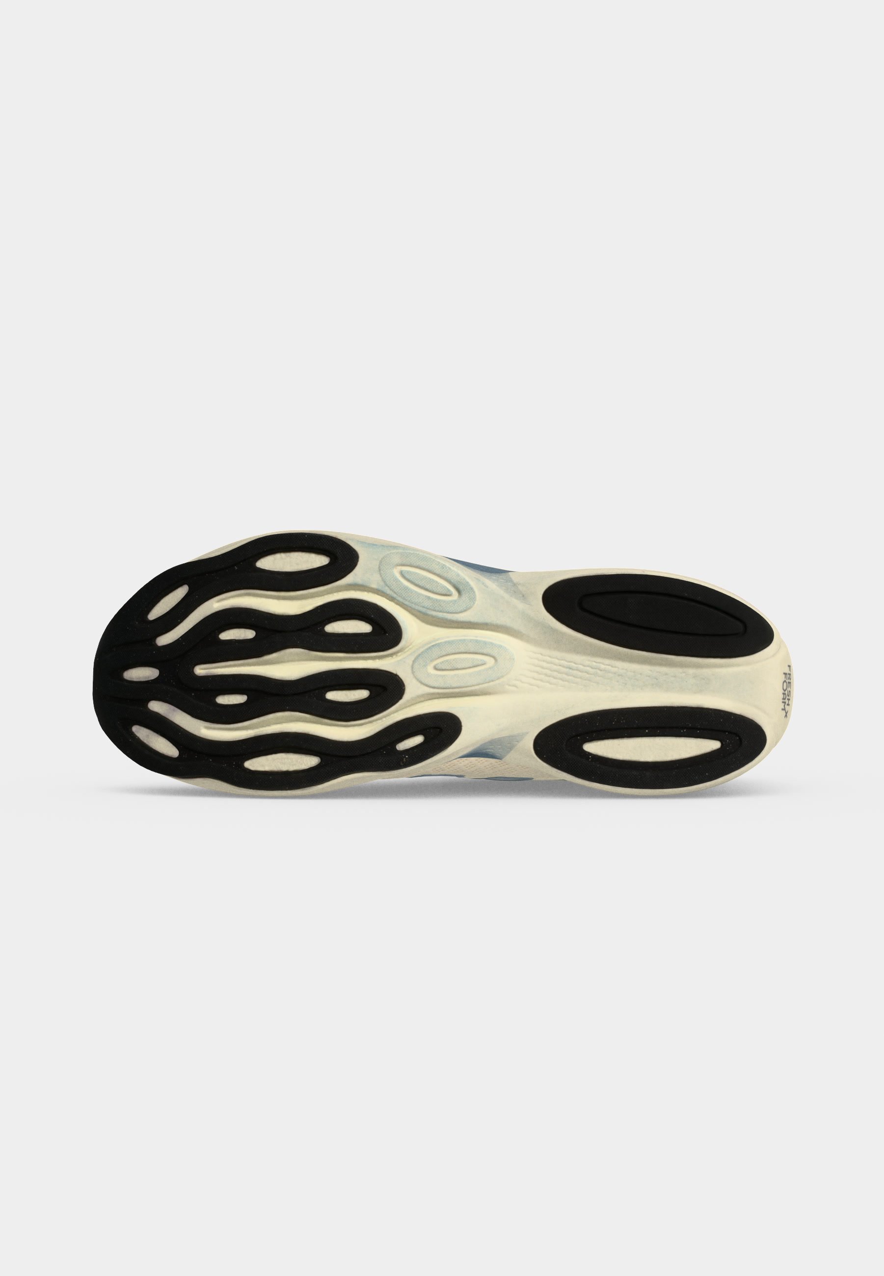 Suela de un zapato deportivo de color claro con patrones de agarre texturizados en negro y fondo blanco.
