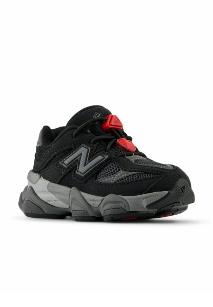 Zapatillas deportivas en negro y gris con parte superior de malla, cuello acolchado, suela de goma y detalles en rojo. Presentan un sistema de cierre sin cordones.