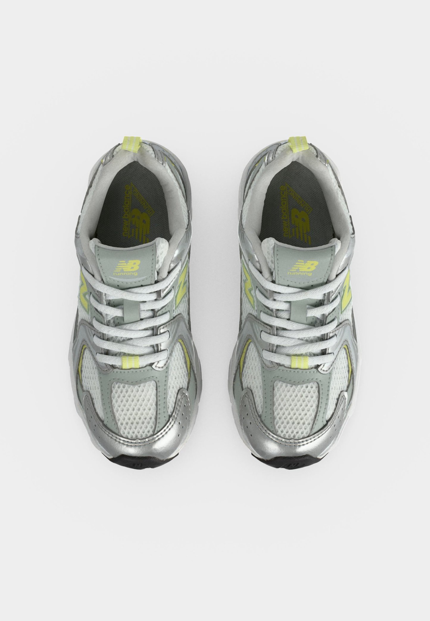 Par de zapatillas de running New Balance plateadas y grises con cordones blancos y detalles en amarillo claro vistas desde arriba sobre fondo blanco.
